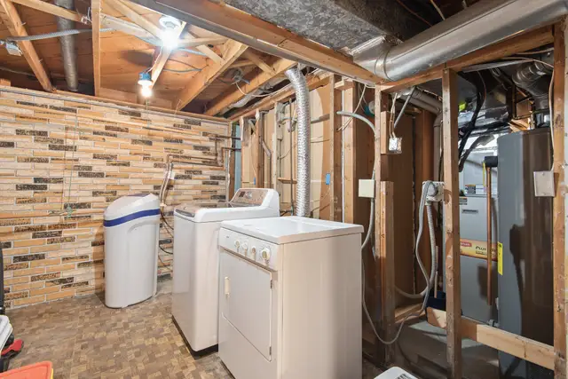 Basement laundry area with a floor drain and exposed framing